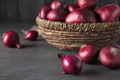 Photo of Fresh whole red onion bulbs on grey table. Space for text