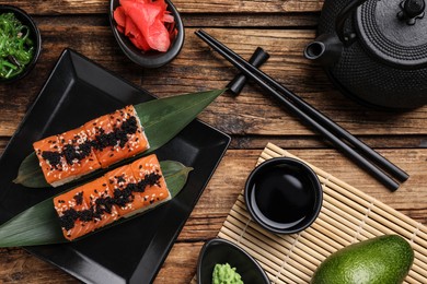 Delicious sushi rolls served on wooden table, flat lay