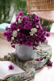Photo of Beautiful flowers, bright cloth and book on wooden table