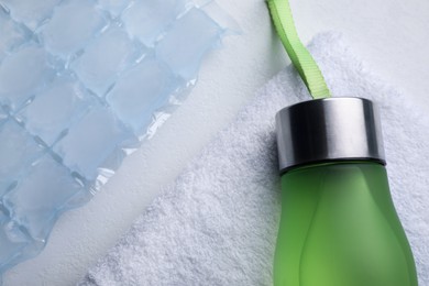 Bottle of water, ice pack and towel on white background, flat lay. Heat stroke treatment