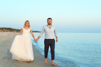 Photo of Wedding couple walking on beach. Space for text