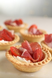 Delicious canapes with jamon, cream cheese and cherry tomatoes on table, closeup