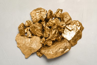 Pile of gold nuggets on light grey table, flat lay