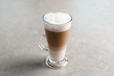 Glass cup of delicious layered coffee on light grey table