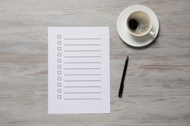 Paper sheet with checkboxes, cup of coffee and pen on white wooden table, flat lay. Checklist