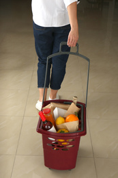 Photo of Woman with shopping basket full of different products, closeup