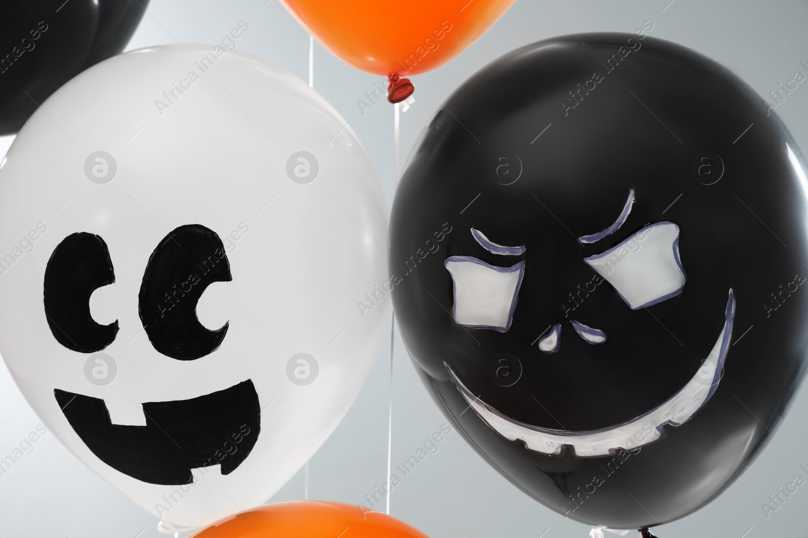 Photo of Spooky balloons for Halloween party on light grey background