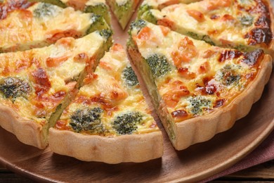 Photo of Delicious homemade quiche with salmon and broccoli on wooden board, closeup