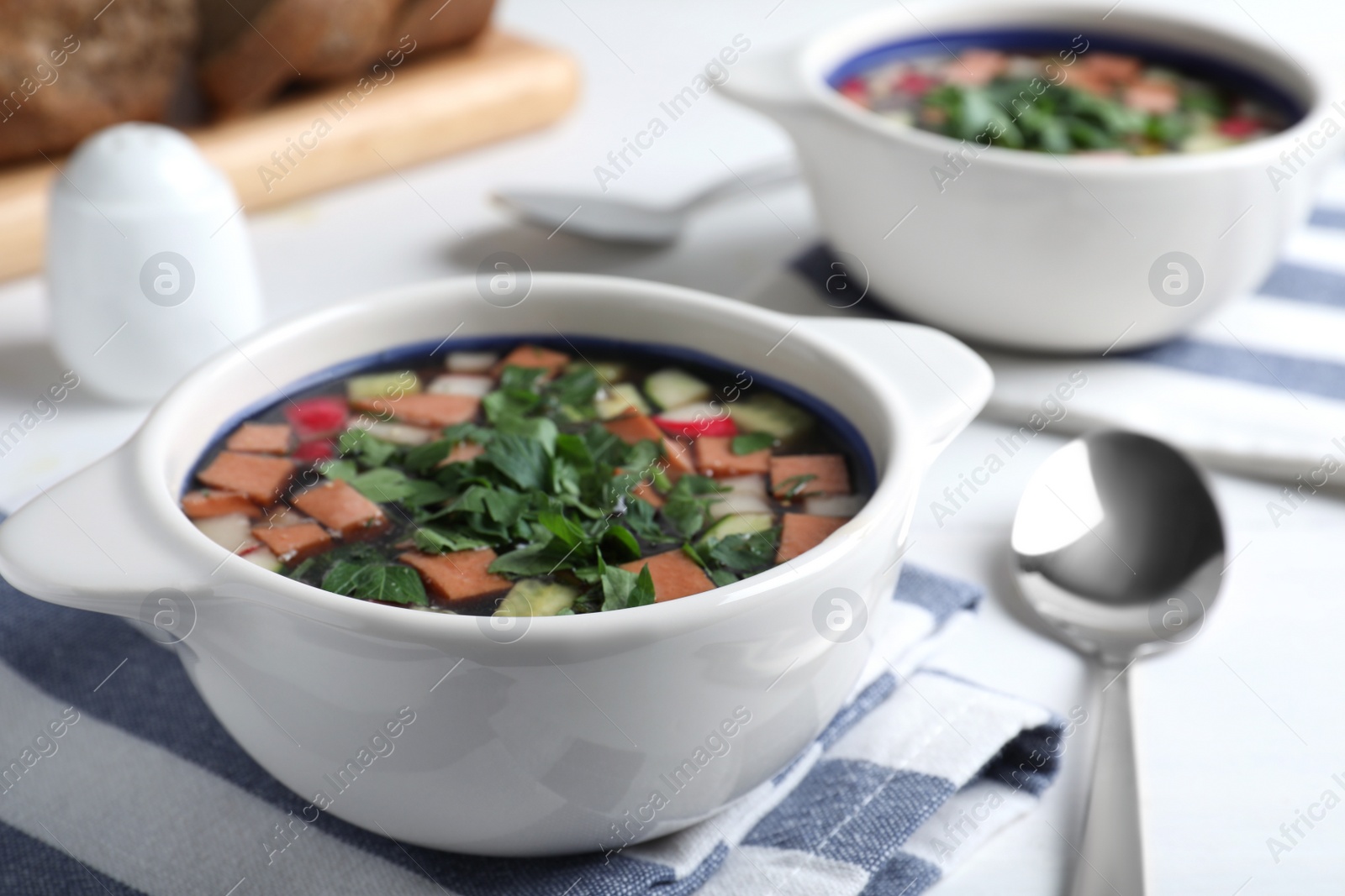 Photo of Delicious cold okroshka with kvass served on white table, closeup. Traditional Russian summer soup