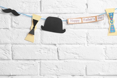 Bow ties, hat and mustache hanging on rope against brick wall background