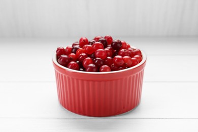 Photo of Fresh ripe cranberries in bowl on white wooden table, closeup