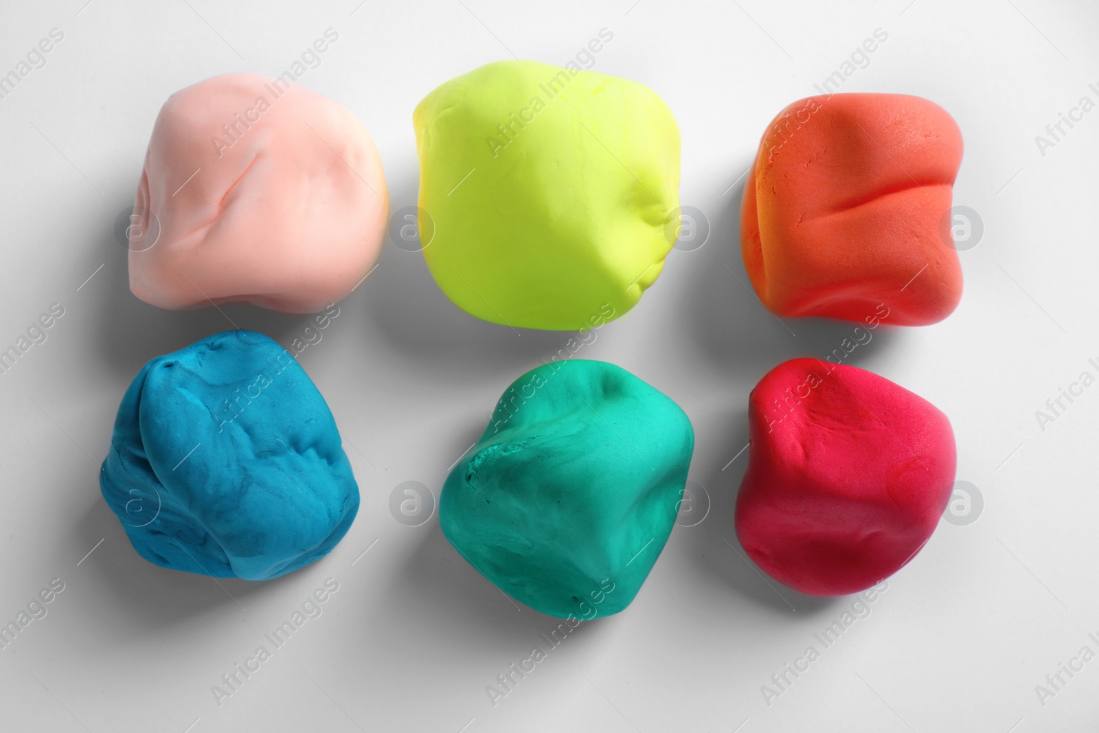 Photo of Different color play dough on white background, top view