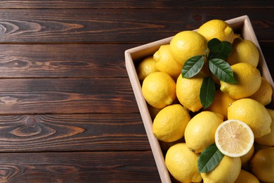 Fresh lemons in crate on wooden table, top view. Space for text