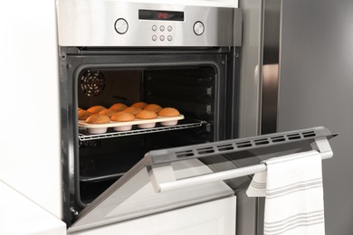 Baking pan with cupcakes in modern oven