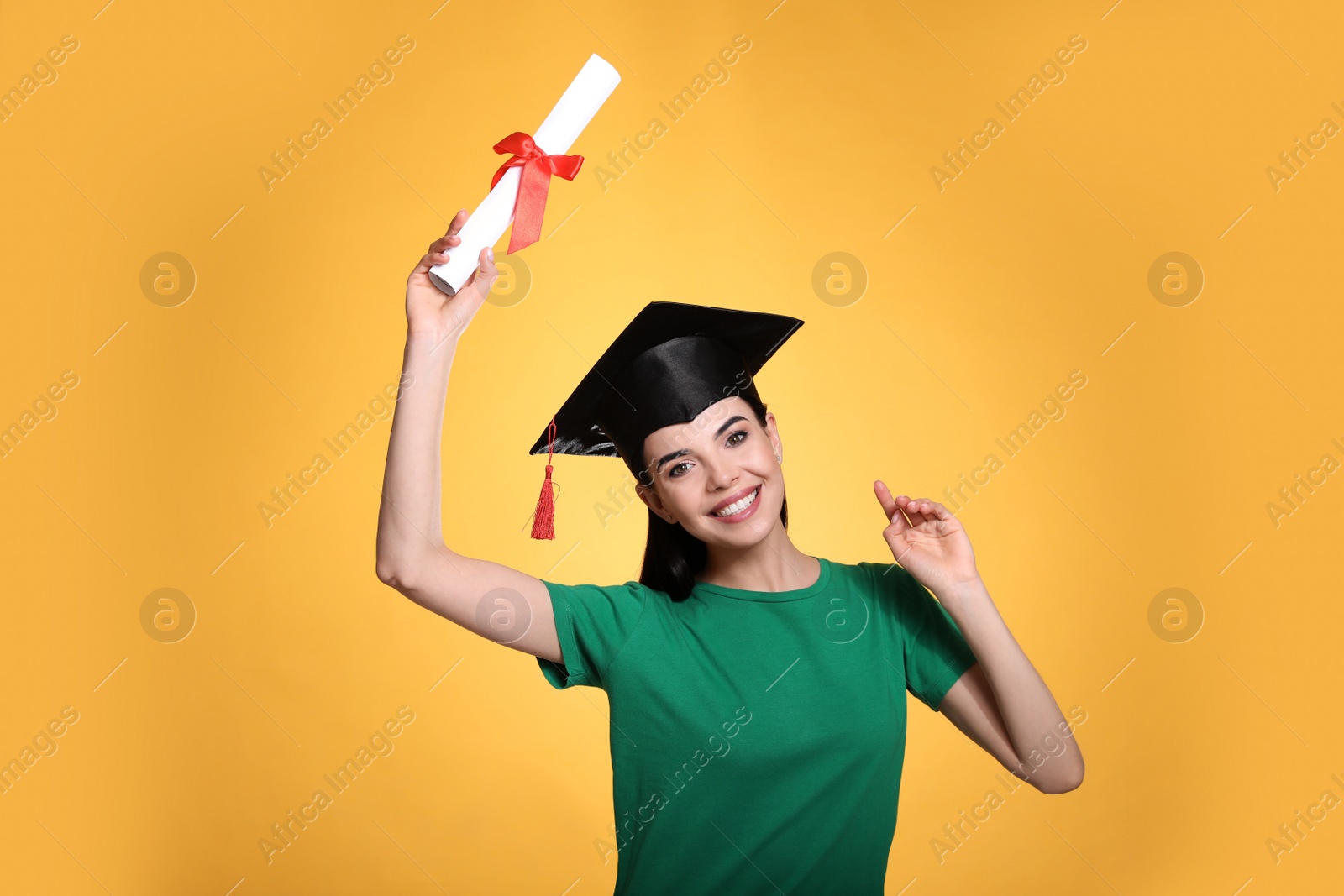 Photo of Happy student with graduation hat and diploma on yellow background