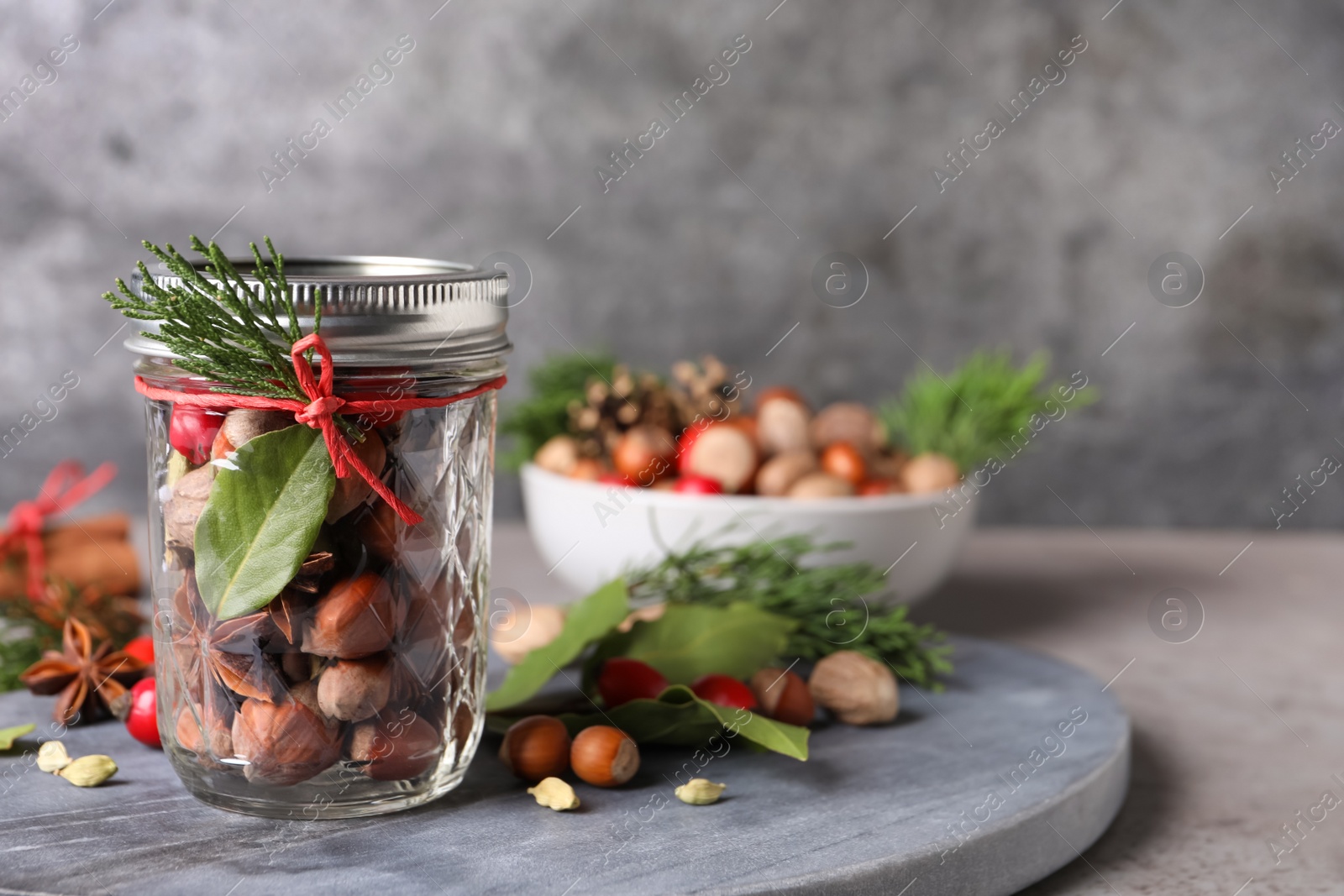 Photo of Aromatic potpourri in glass jar on grey table. Space for text