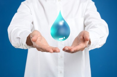 Woman holding image of water drop on blue background, closeup