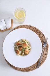 Delicious scallop pasta with spices in bowl served on white table, flat lay