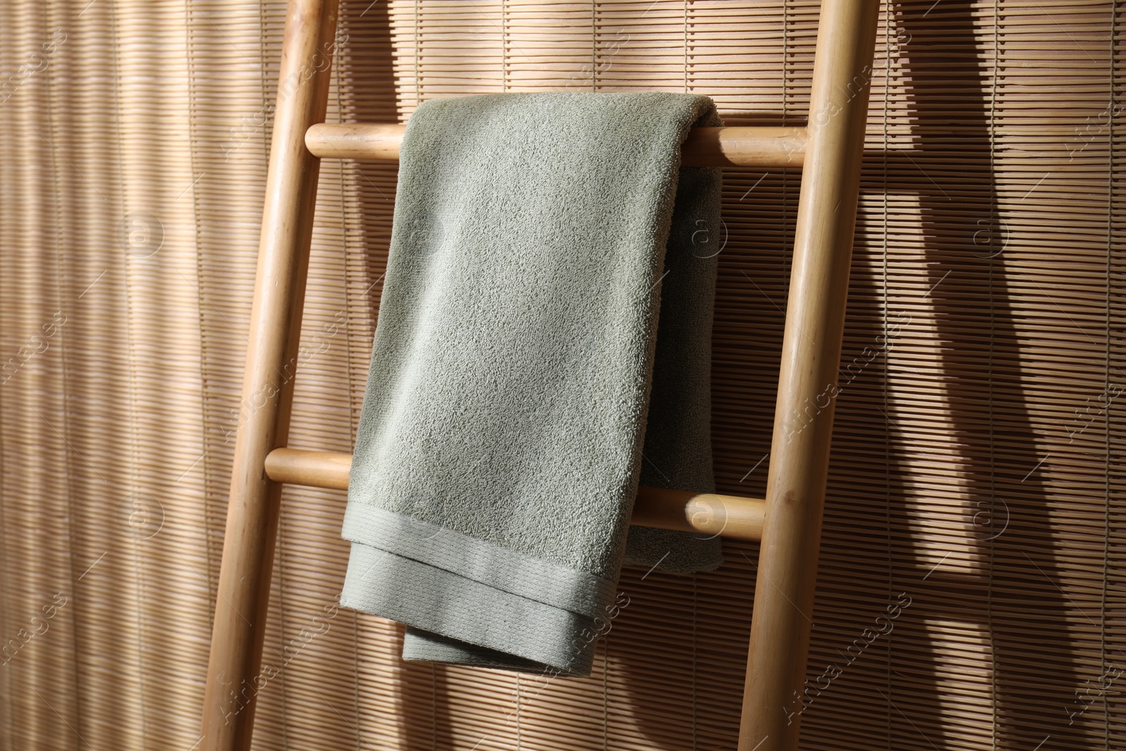 Photo of Green terry towel on wooden ladder indoors