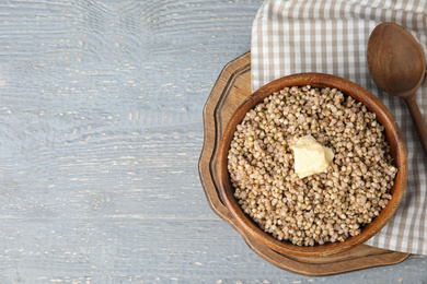 Tasty buckwheat porridge with butter on grey wooden table, flat lay. Space for text