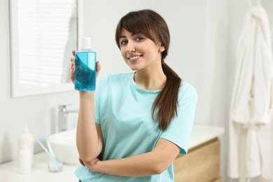 Photo of Young woman with mouthwash in bathroom. Oral hygiene