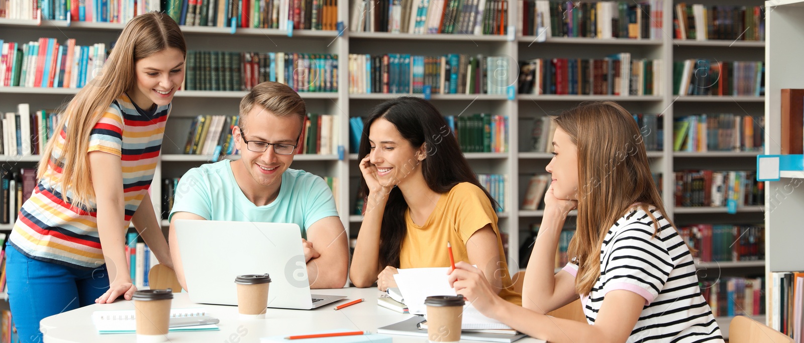 Image of Young students discussing group project at table in library. Banner design