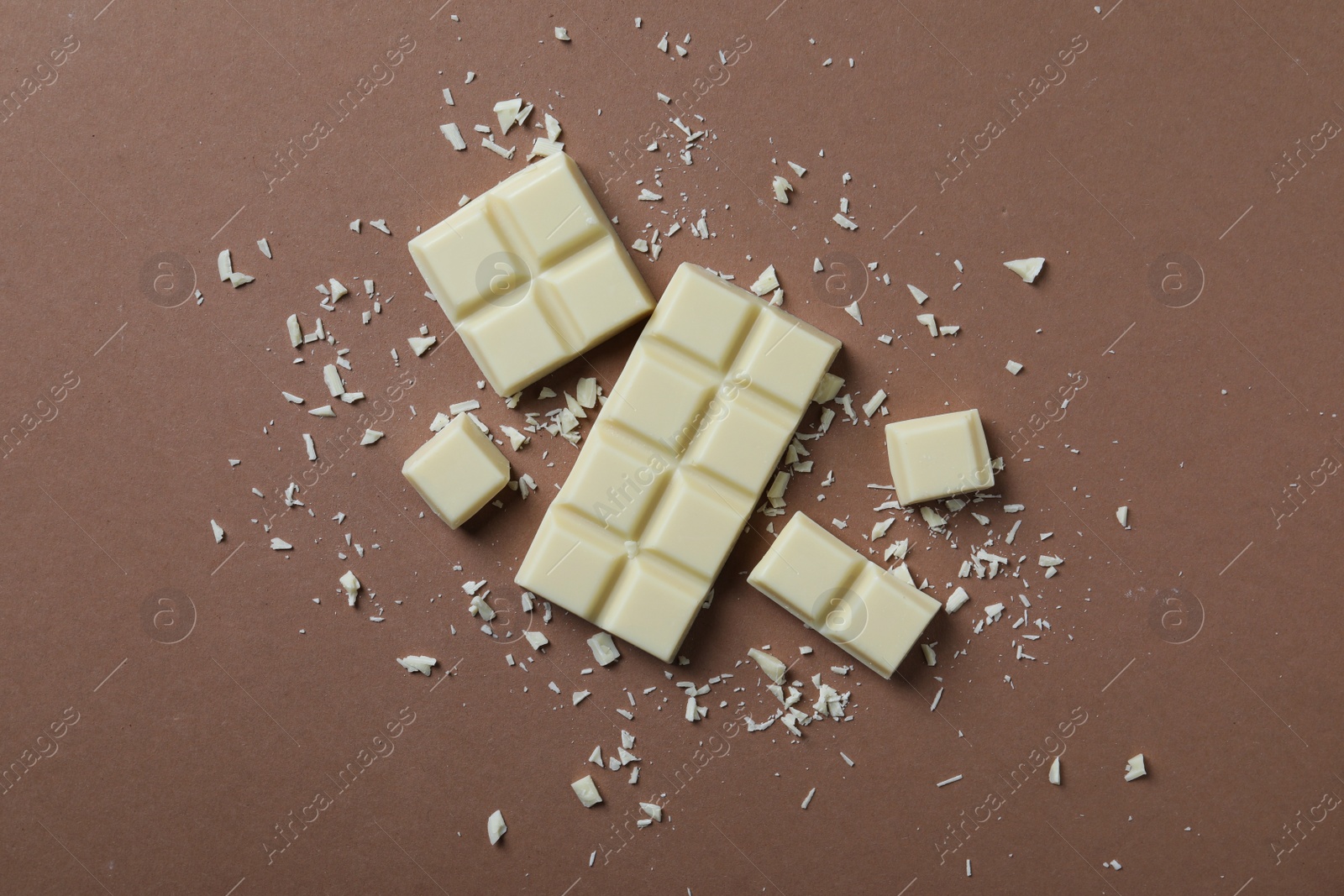 Photo of Tasty white chocolate on brown background, flat lay