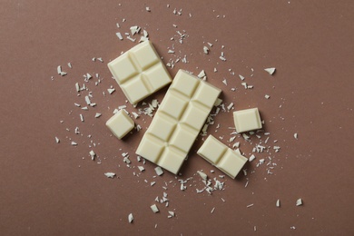 Photo of Tasty white chocolate on brown background, flat lay