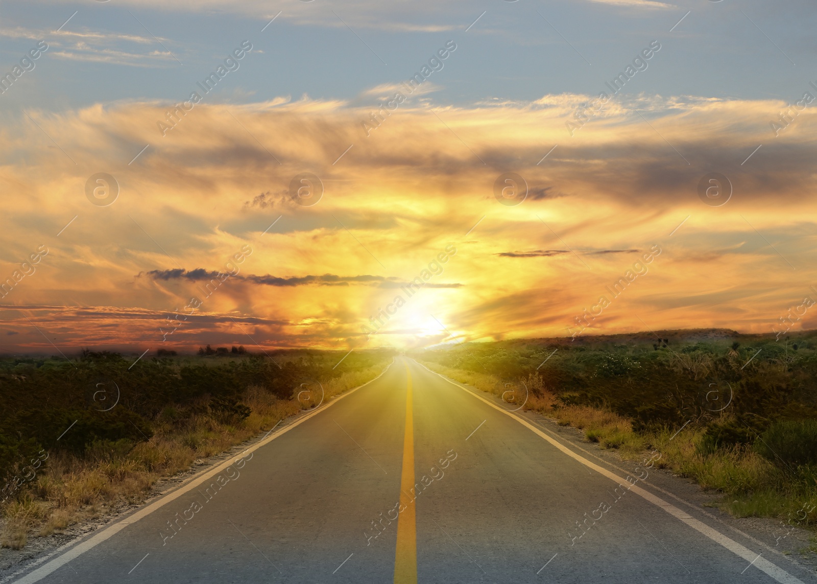 Image of Empty asphalt road through field at sunset