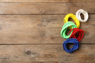 Photo of Colorful shoelaces on wooden background, flat lay. Space for text