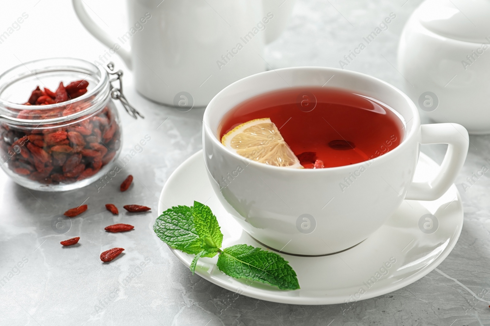 Photo of Cup of healthy goji tea with lemon on grey table