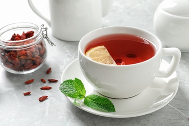 Photo of Cup of healthy goji tea with lemon on grey table