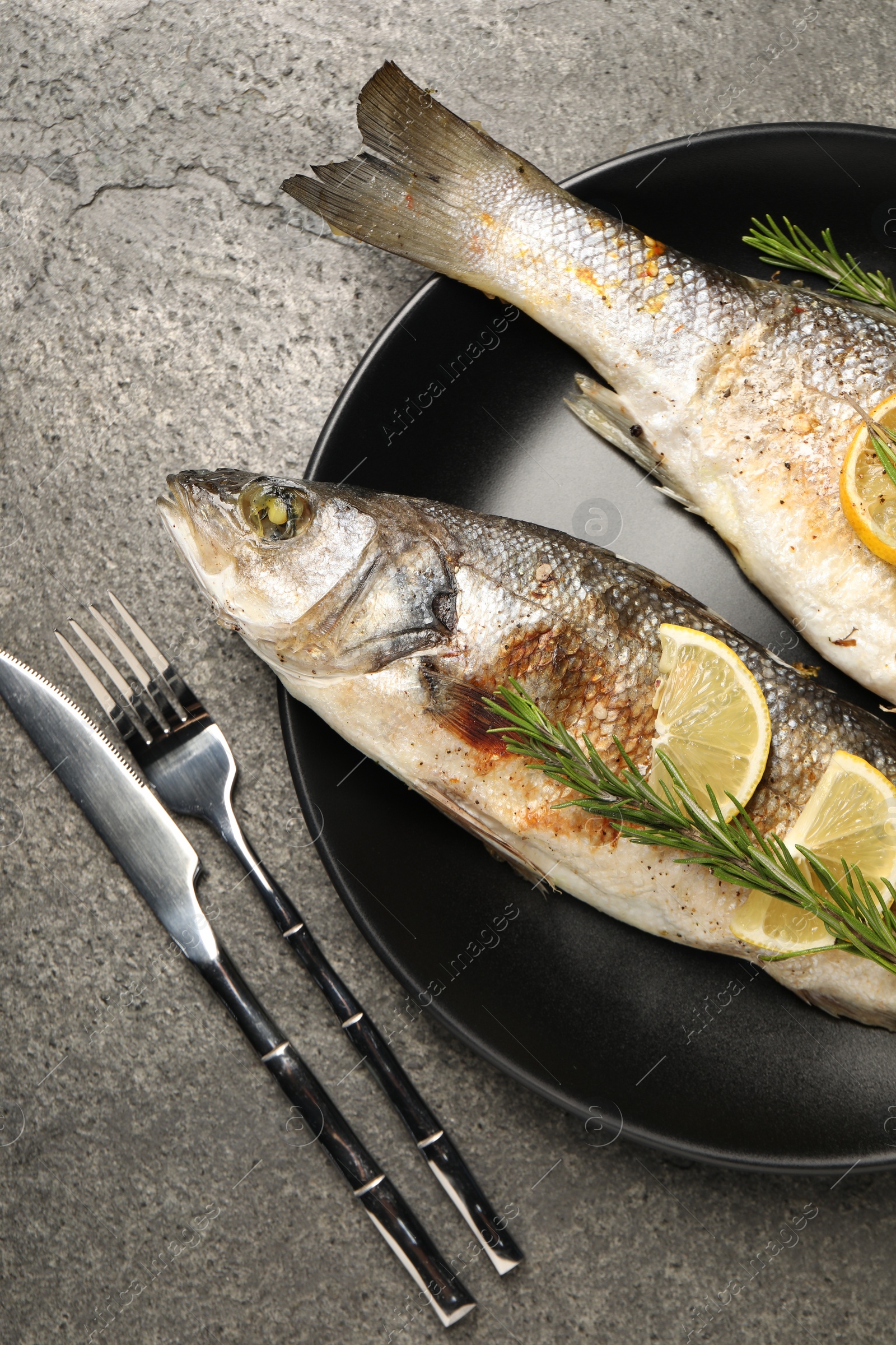 Photo of Delicious baked fish served on grey table, top view