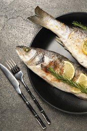 Photo of Delicious baked fish served on grey table, top view