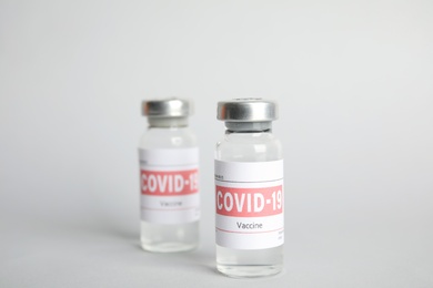 Vials with coronavirus vaccine on light background