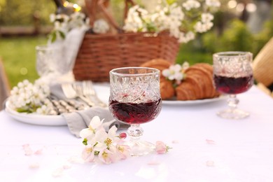 Photo of Stylish table setting with beautiful spring flowers, wine and croissants in garden