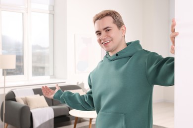 Photo of Happy man inviting to come in room