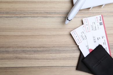 Photo of Avia tickets, passports and plane on wooden table, flat lay with space for text. Travel agency concept