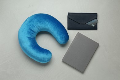 Photo of Light blue travel pillow, notebook and wallet with credit card on gray background, flat lay