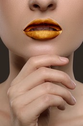 Image of Young woman with beautiful gold lips on grey background, closeup