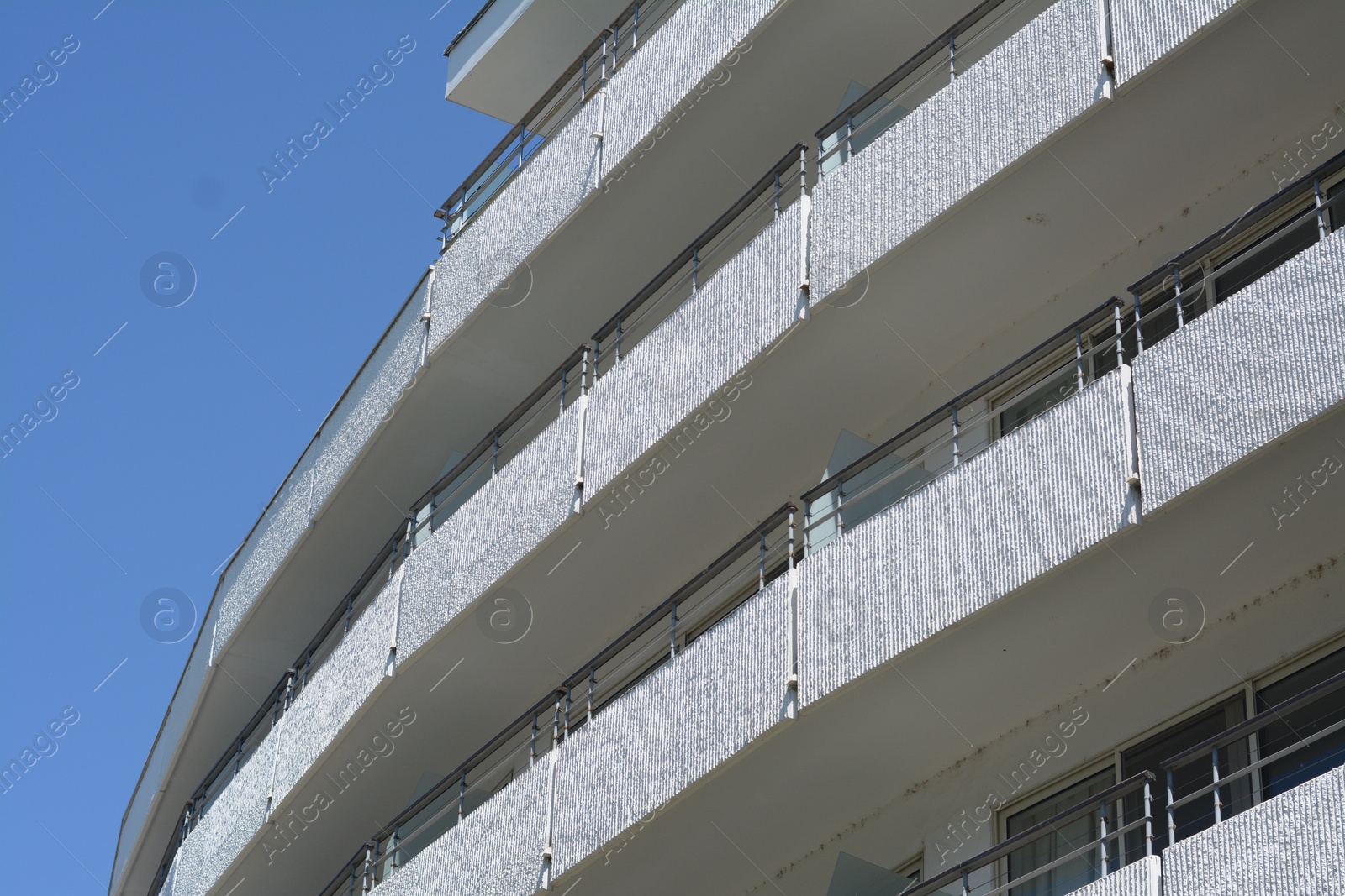 Photo of Exterior of beautiful residential building with balconies against blue sky