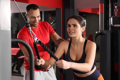 Trainer explaining woman how to do exercise properly in modern gym