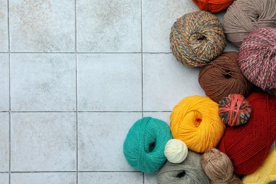Photo of Soft woolen yarns on grey tiled background, flat lay. Space for text