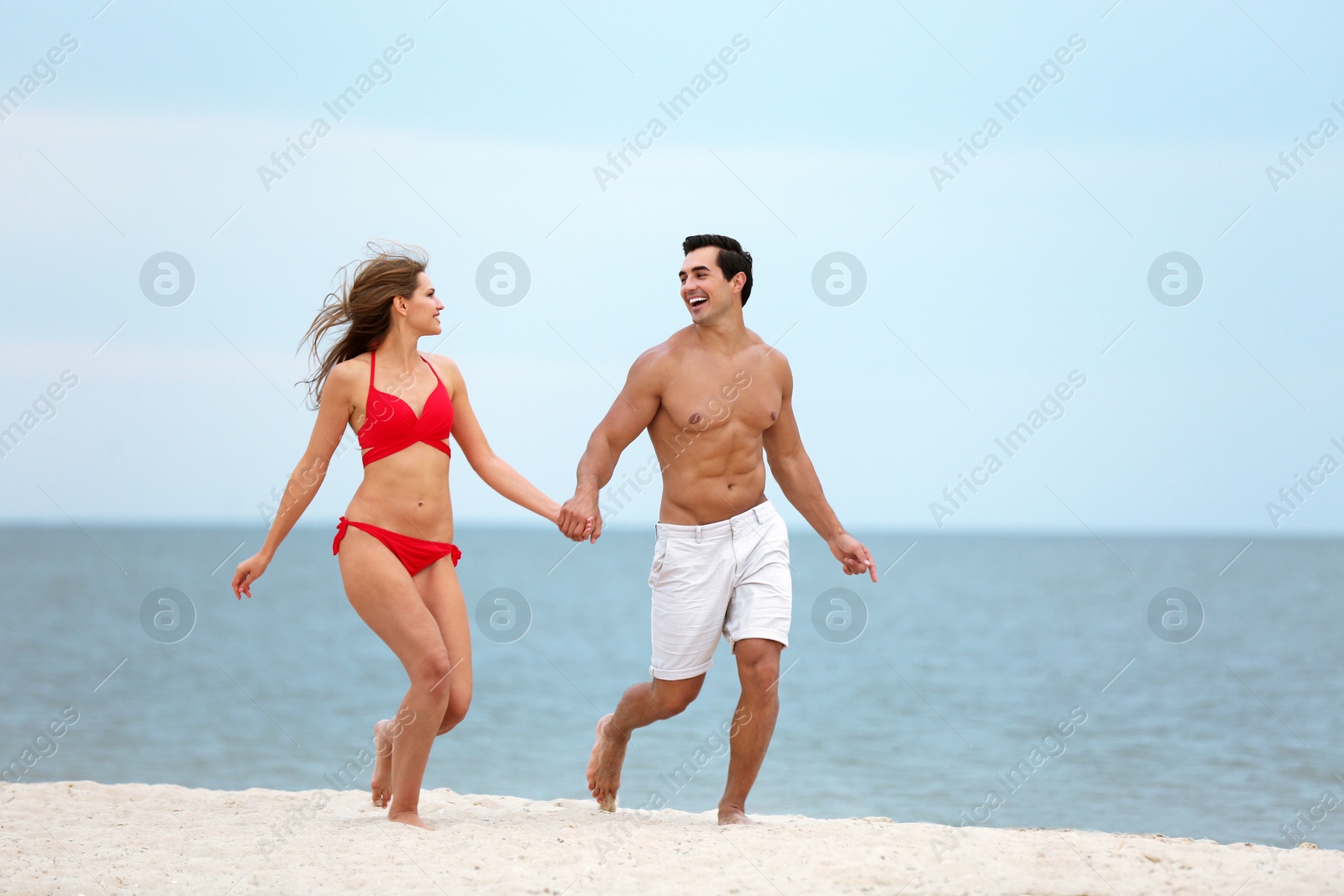 Photo of Happy young couple running together on sea beach