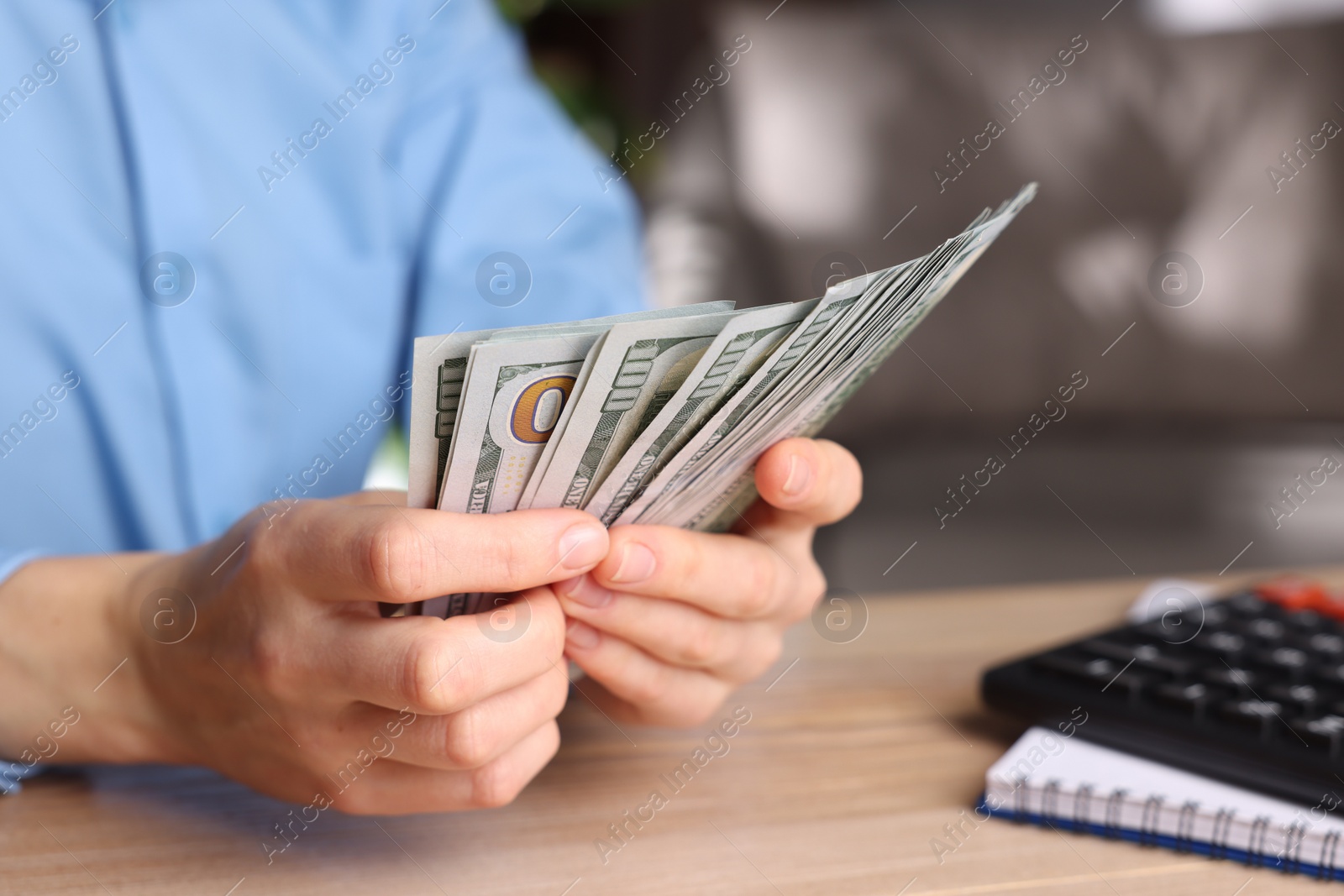 Photo of Money exchange. Woman counting dollar banknotes at wooden table, closeup