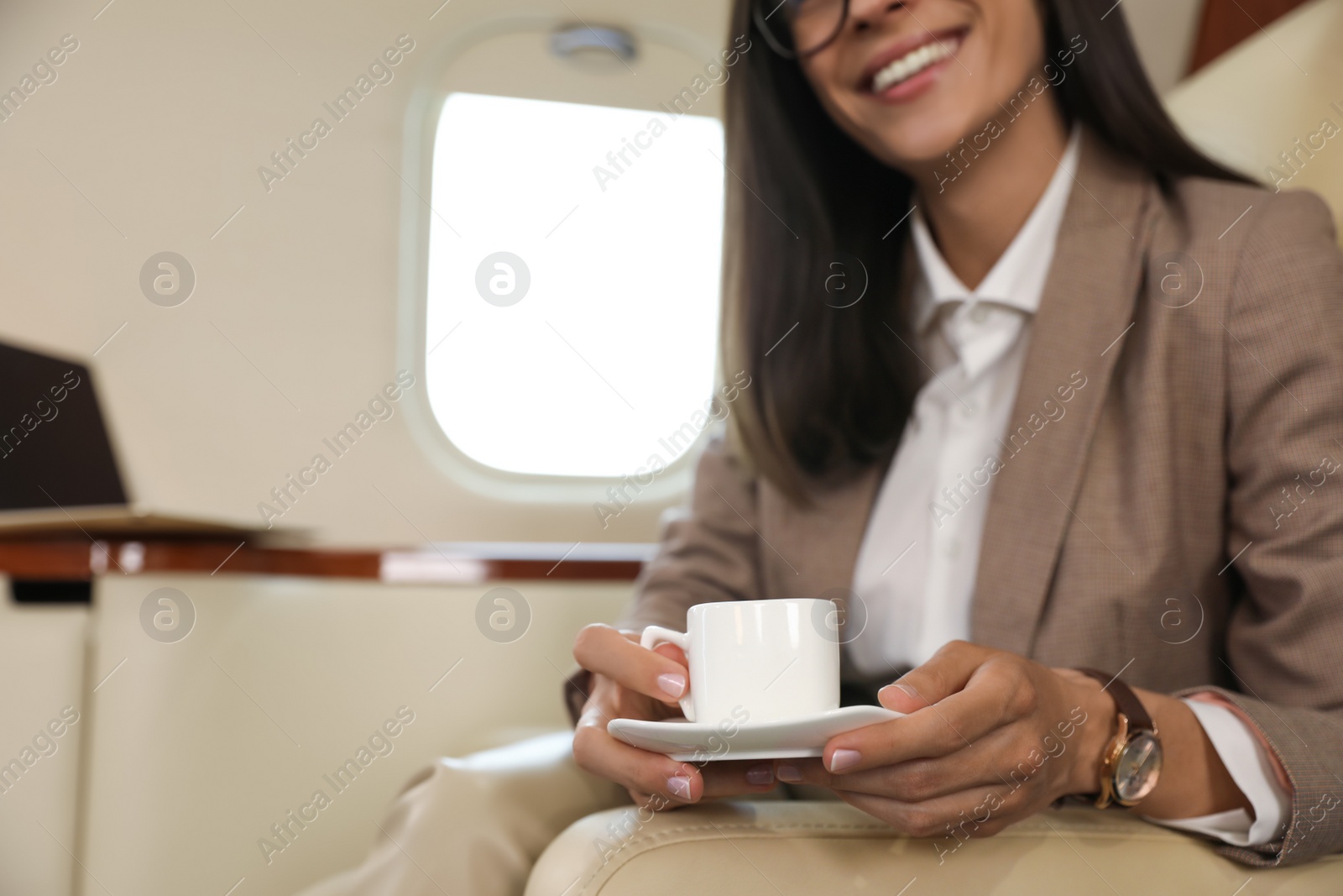 Photo of Businesswoman with cup of coffee in airplane during flight, closeup