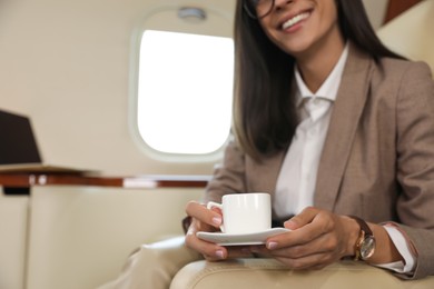 Photo of Businesswoman with cup of coffee in airplane during flight, closeup