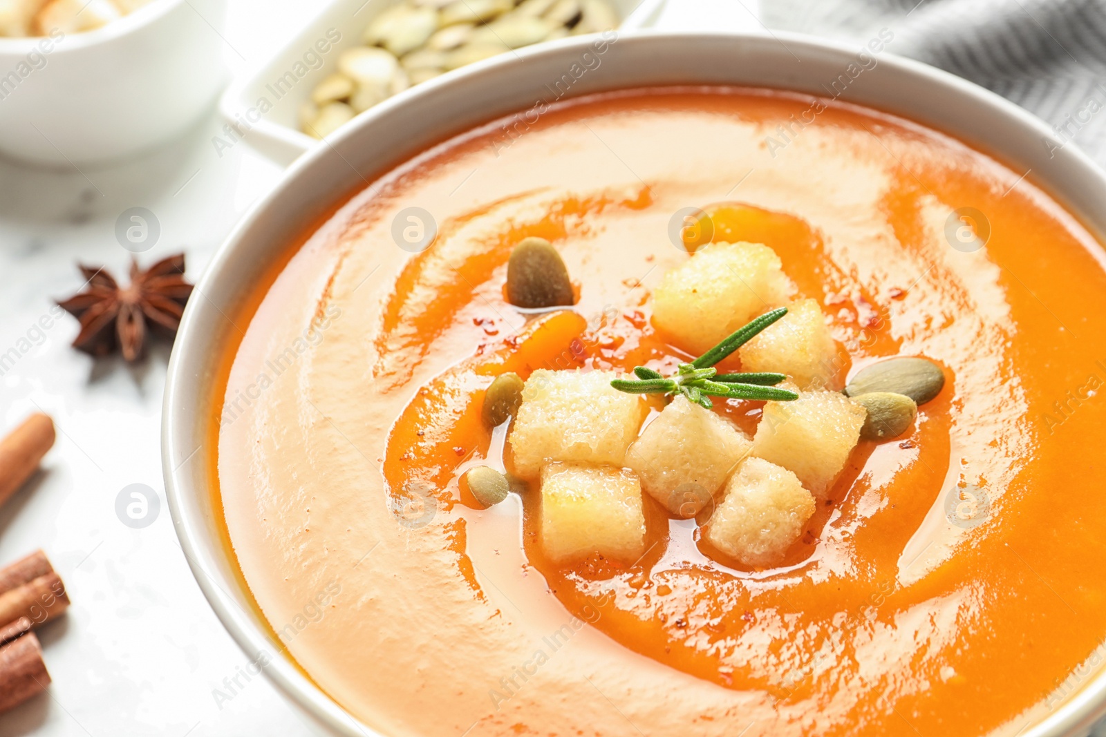 Photo of Bowl of tasty sweet potato soup on table, closeup. Space for text