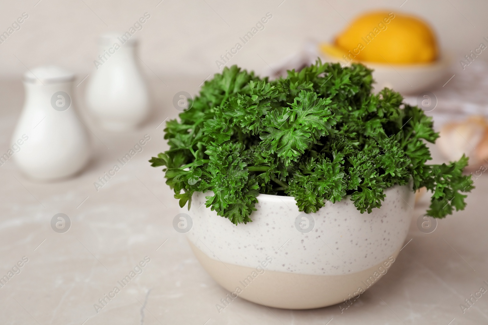 Photo of Bowl with fresh curly parsley on table