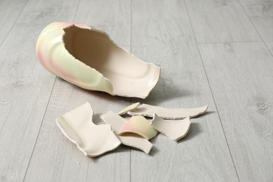 Broken bright ceramic vase on wooden floor